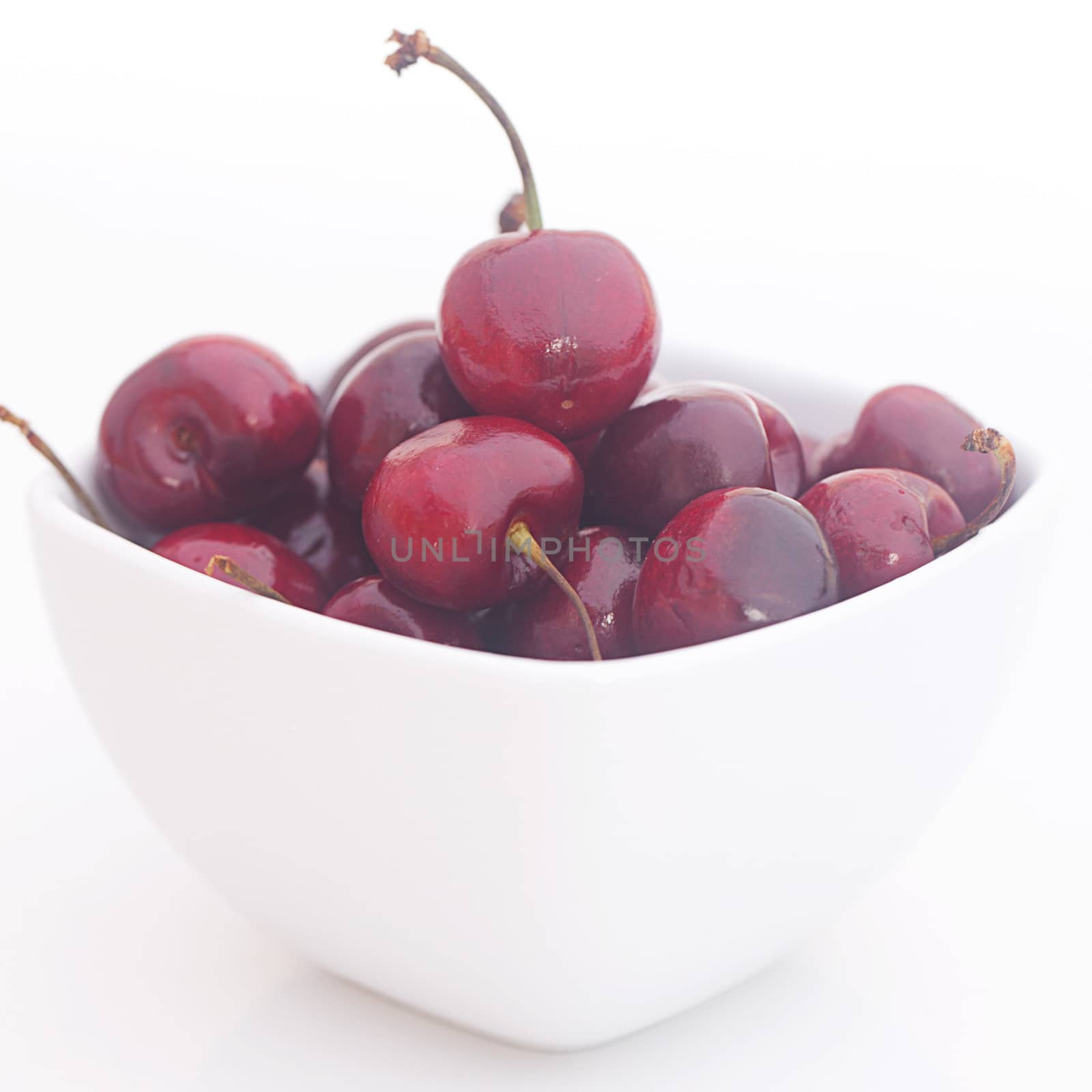 Cherries in a ceramic bowl isolated on white by jannyjus