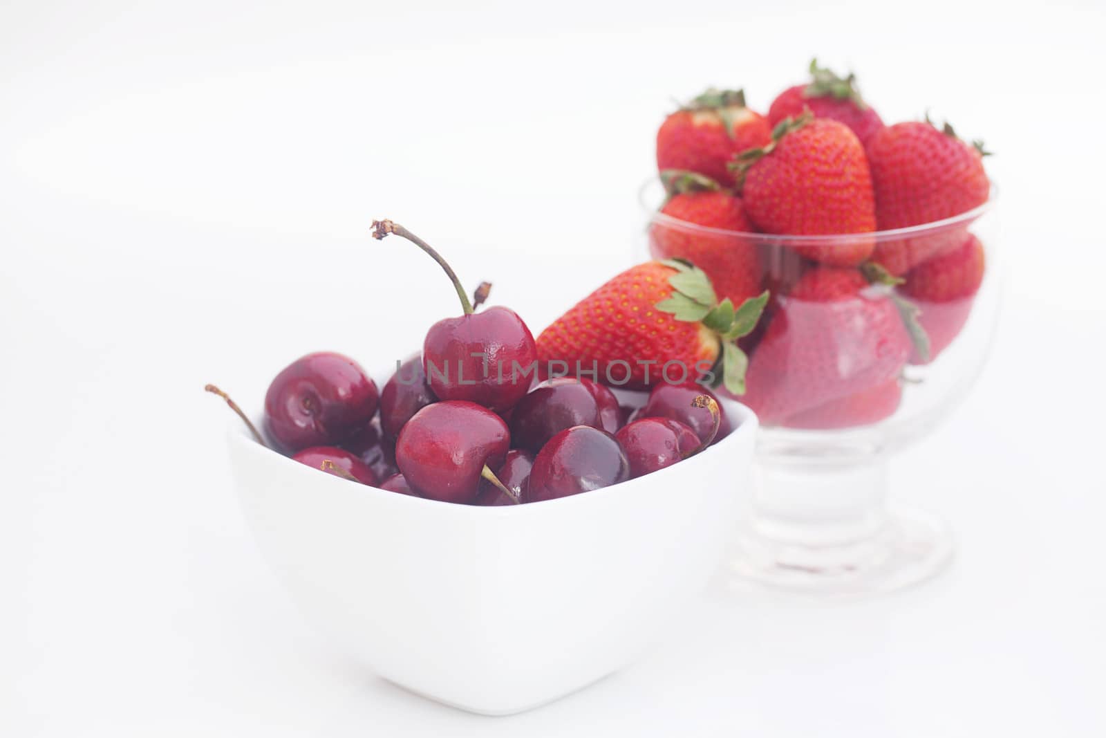 Cherries and strawberry in a ceramic and glass bowl isolated on  by jannyjus