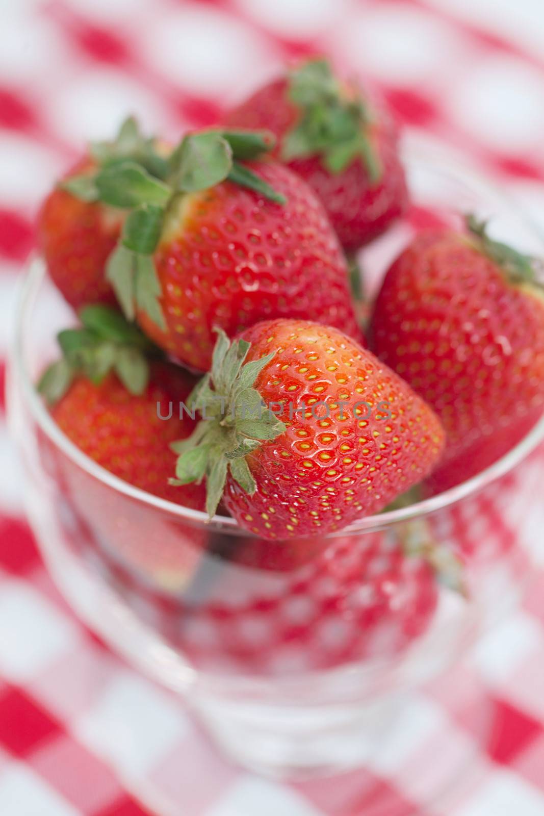 strawberry in a glass bowl on checkered fabric