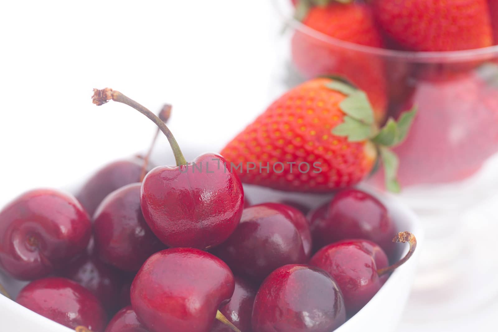 Cherries and strawberry in a ceramic and glass bowl isolated on  by jannyjus