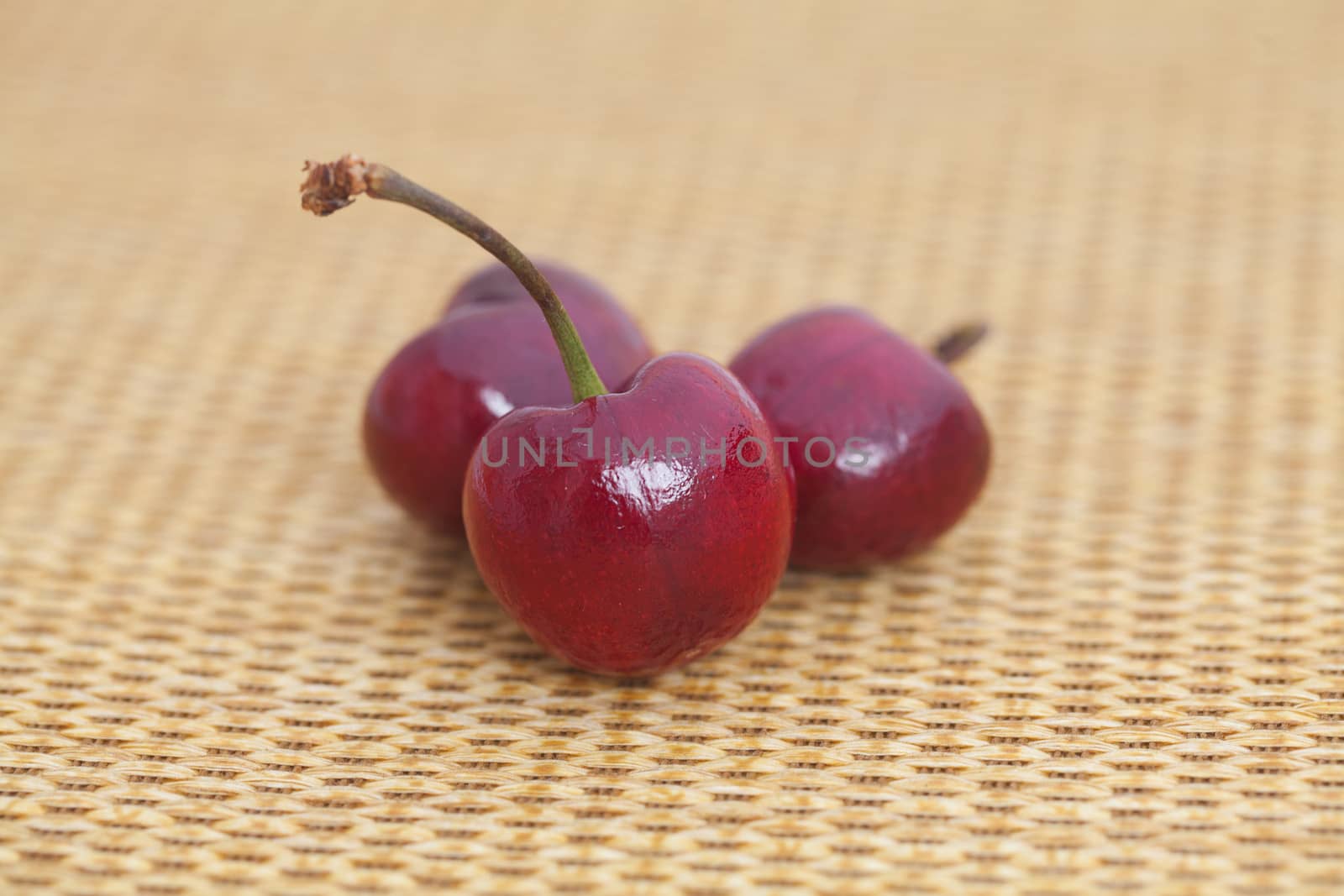 three cherries on wicker mat by jannyjus