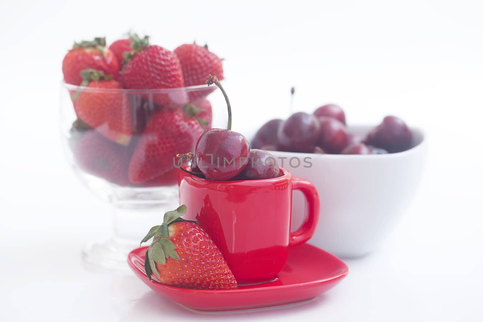 Cherries and strawberry in a ceramic and glass bowl isolated on  by jannyjus