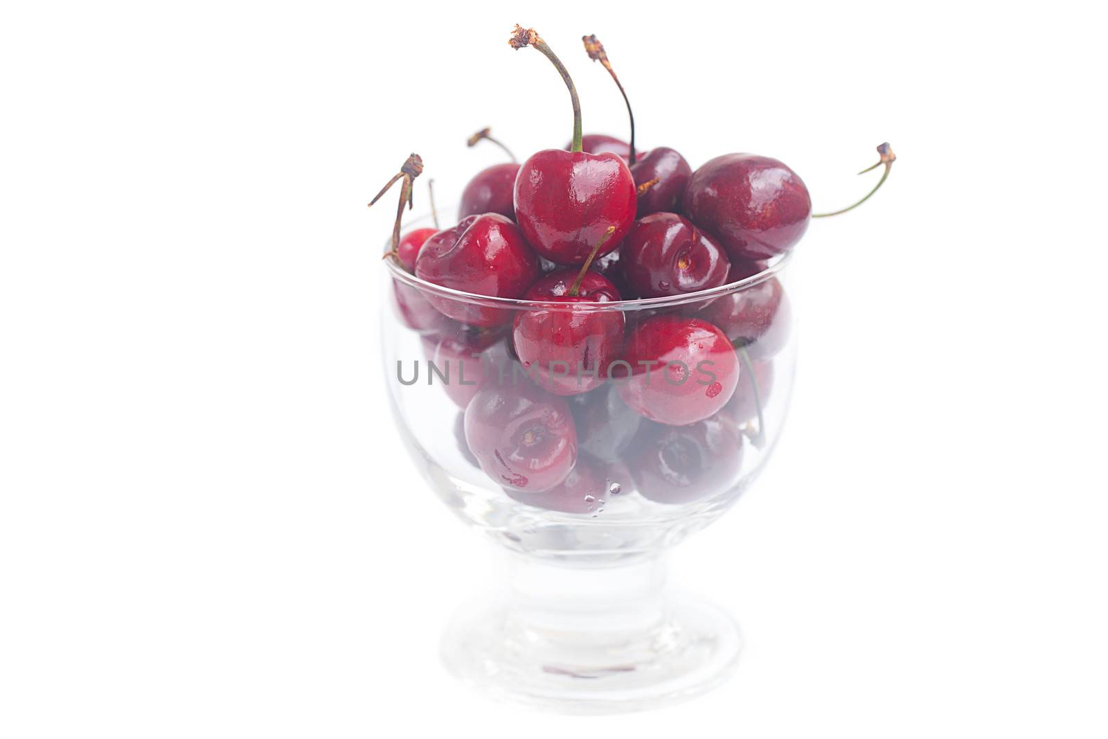 Cherries in a glass bowl isolated on white by jannyjus