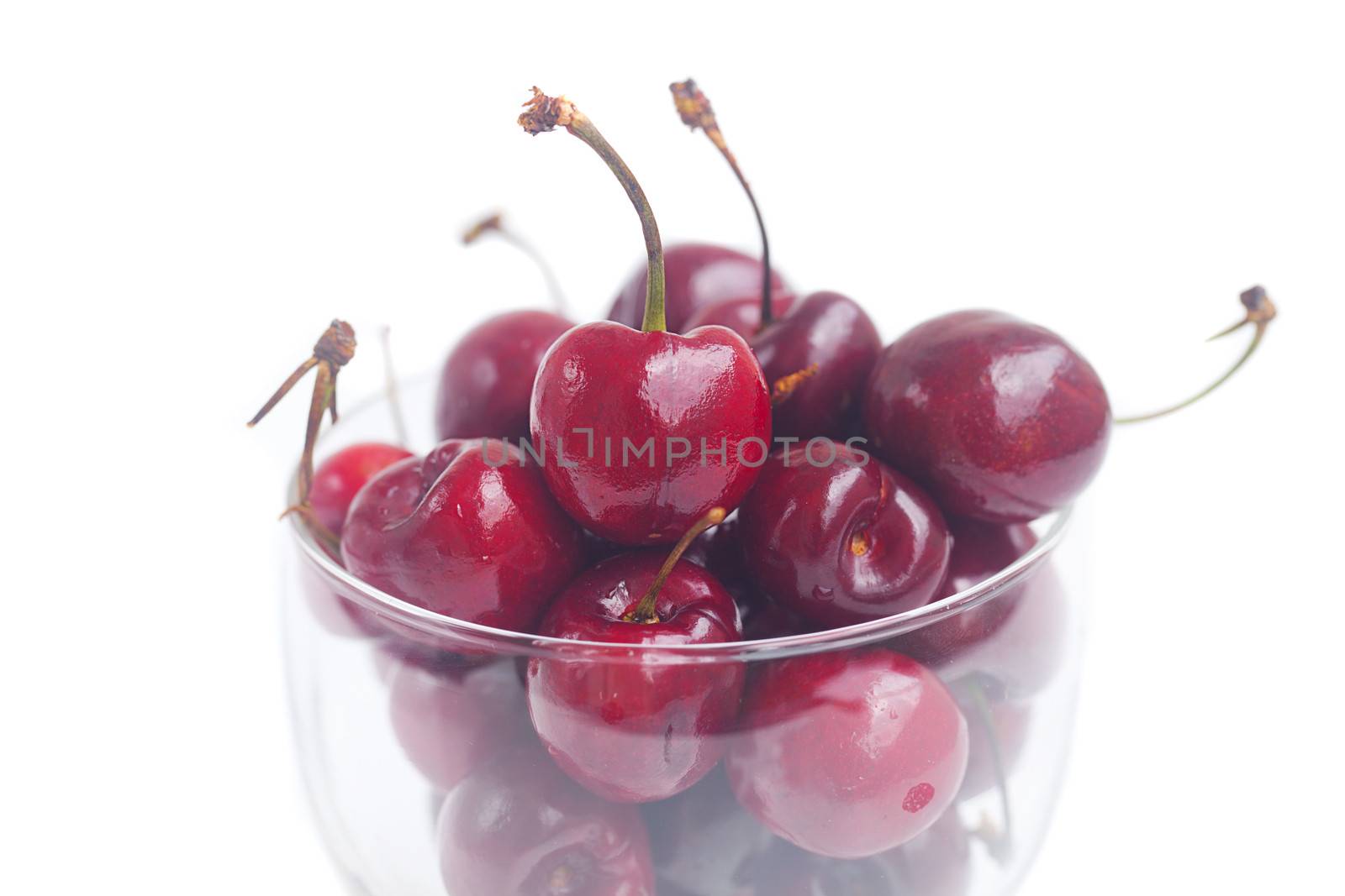 Cherries in a glass bowl isolated on white by jannyjus