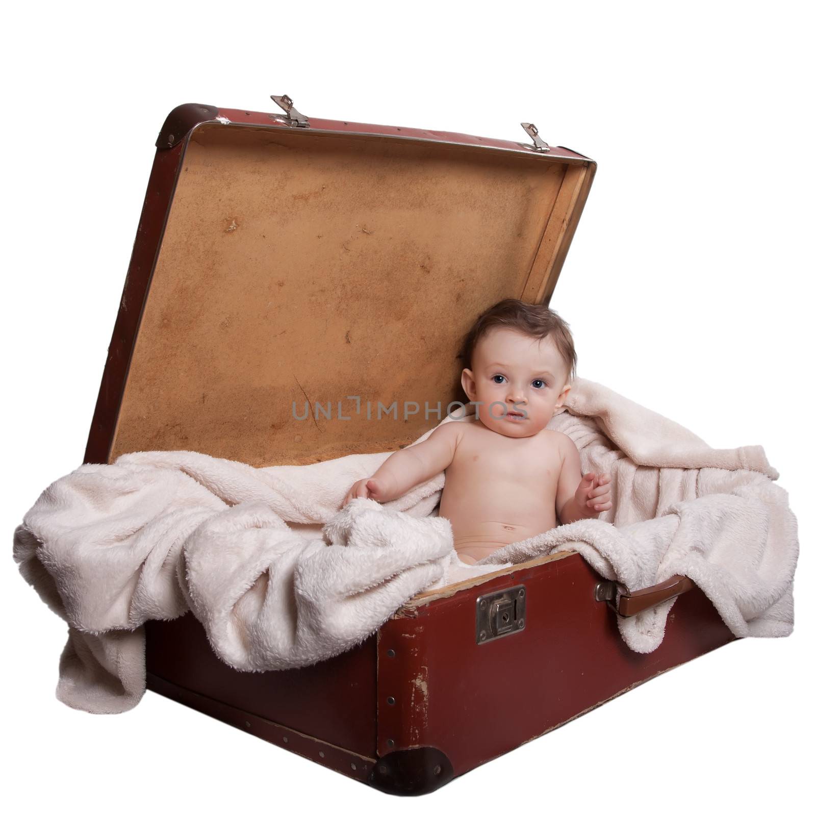 Little baby boy sitting naked on a blanket, in the old suitcases, on a white background