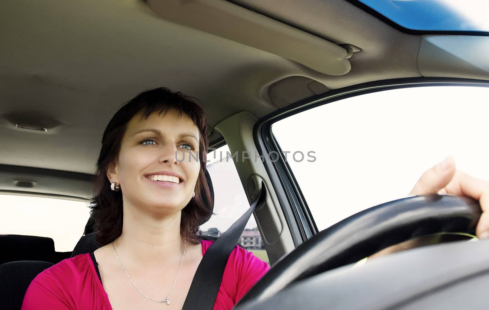 front view of smiling brunette woman driving car