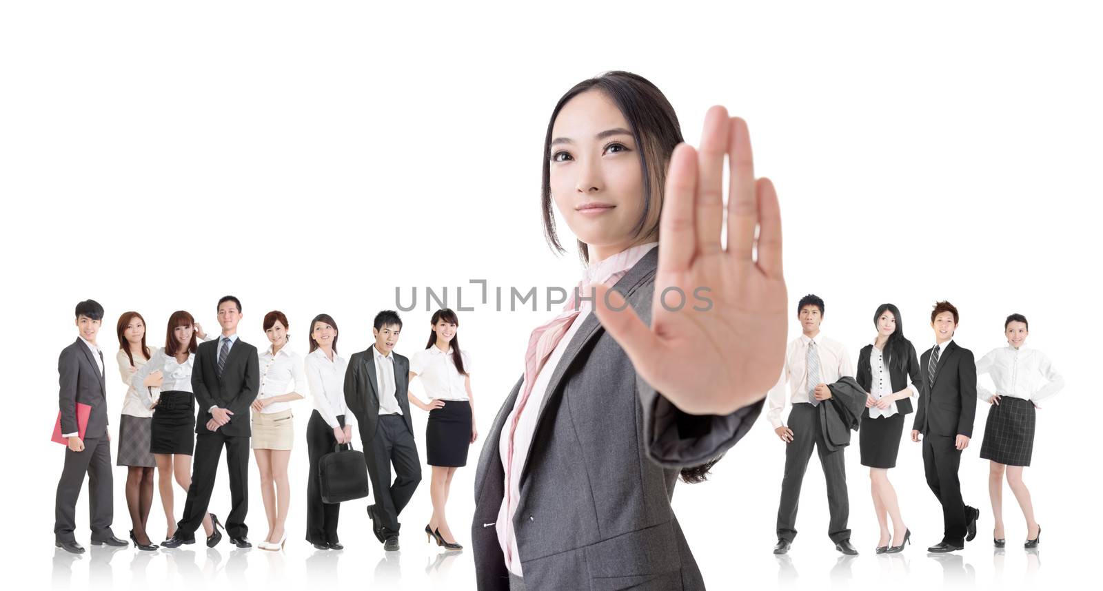Attractive Asian business woman give you a stop sign and stand in front of her team.