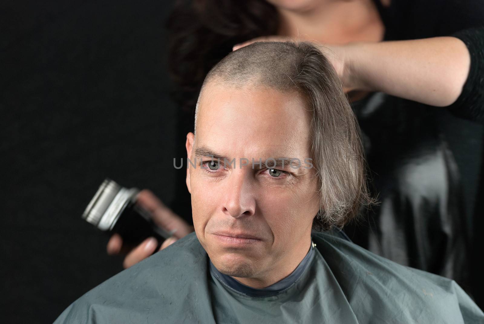 Close-up of a mourning man getting his long hair is shaved off for a cancer fundraiser.
