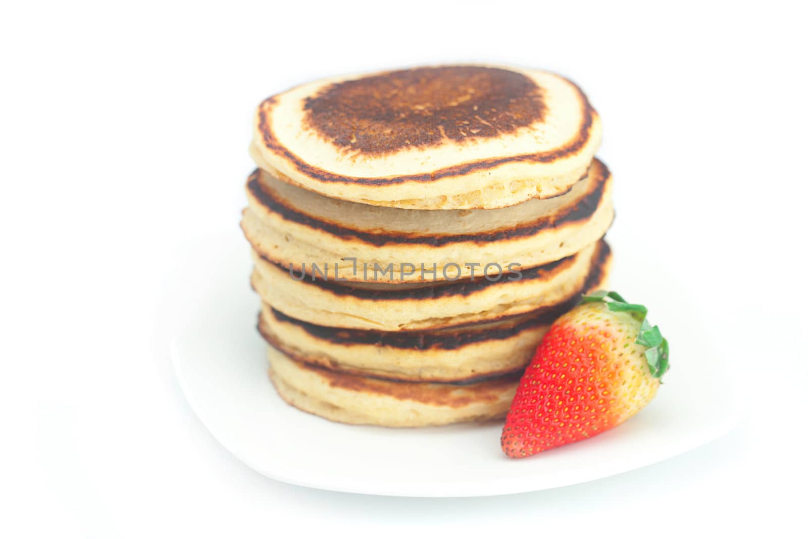 Pancakes and strawberries on a plate isolated on white