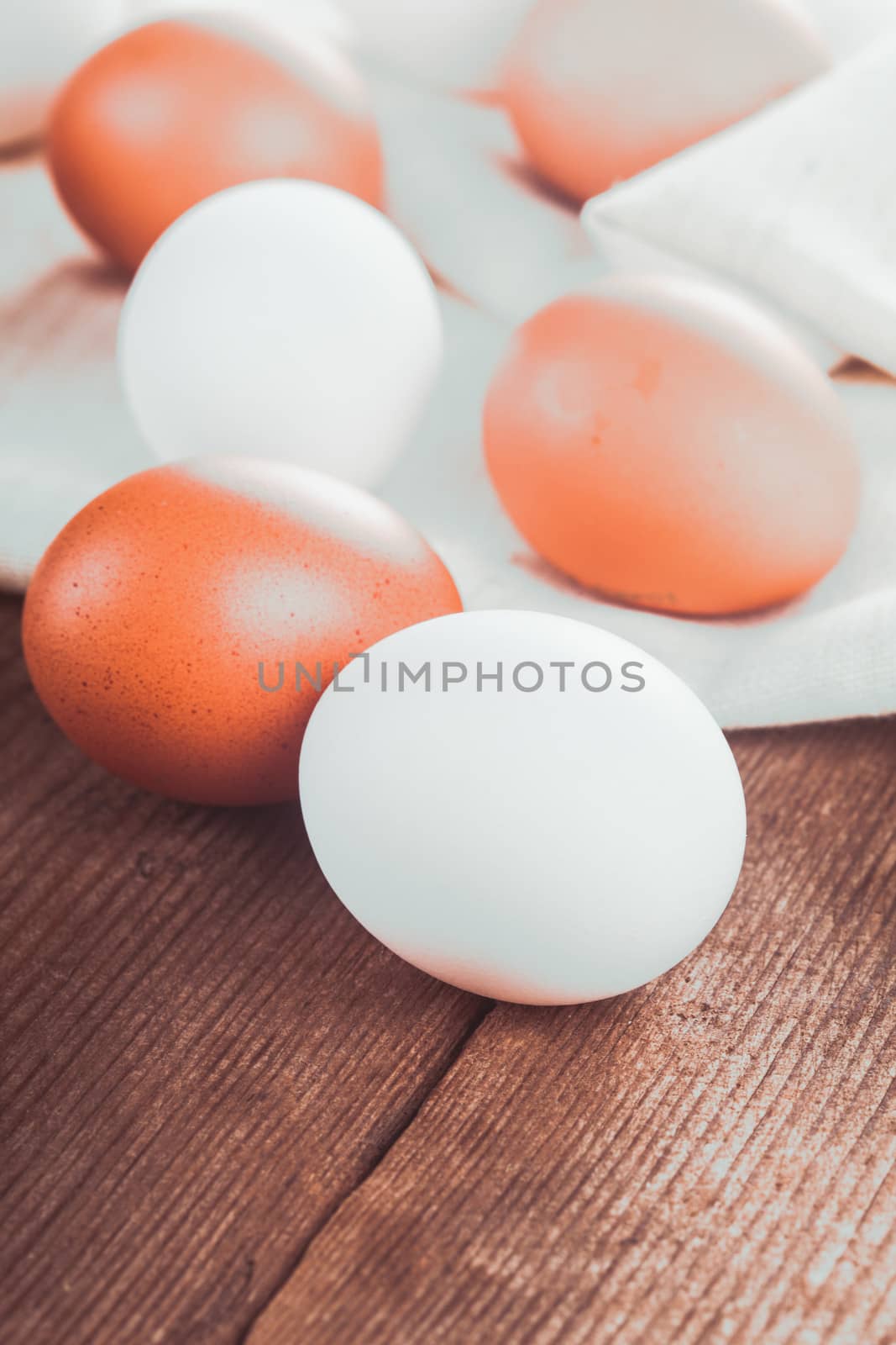 Beige and white chicken eggs on textile tablecloth over rustic wooden table