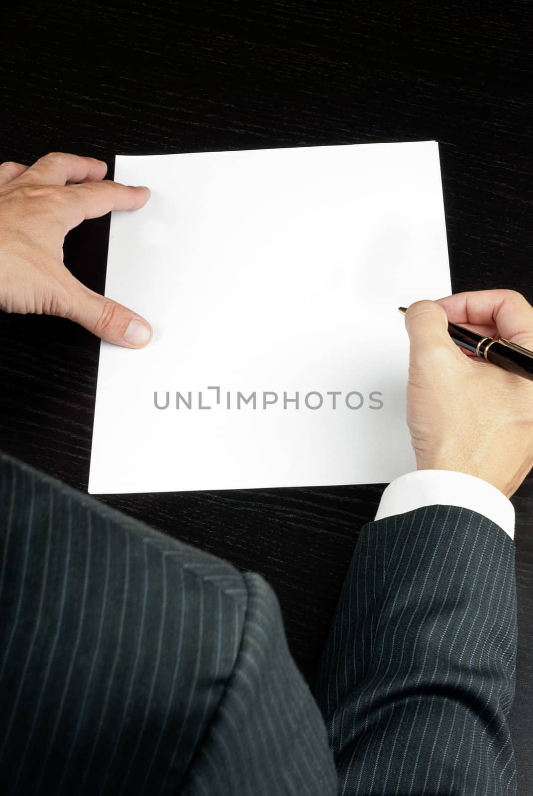 Close-up of a businessman writing, shot from over the shoulder.