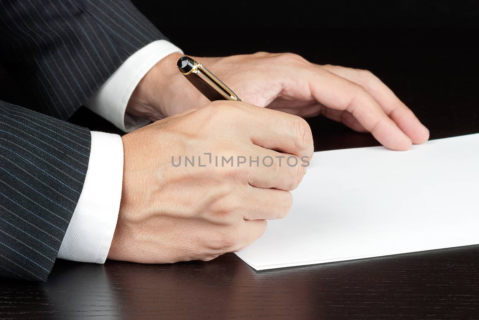 Close-up of a businessman writing, shot from the side.