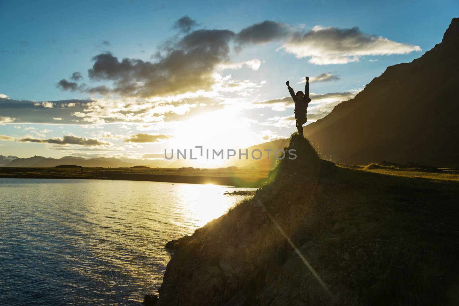 Silhouette boy staying on hill over the sun, Iceland by Tetyana