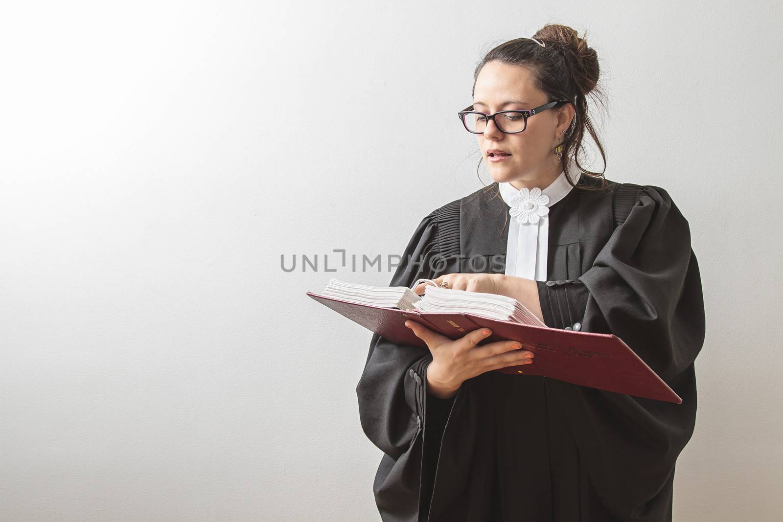 thirty something brunette woman wearing a canadian lawyer toga, reciting from a red criminal law book