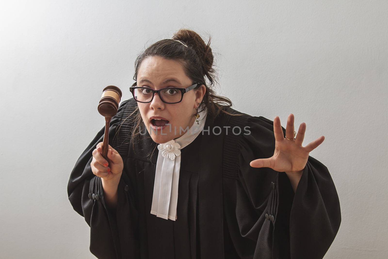 thirty something brunette woman wearing a canadian lawyer toga with a gavel in her hands