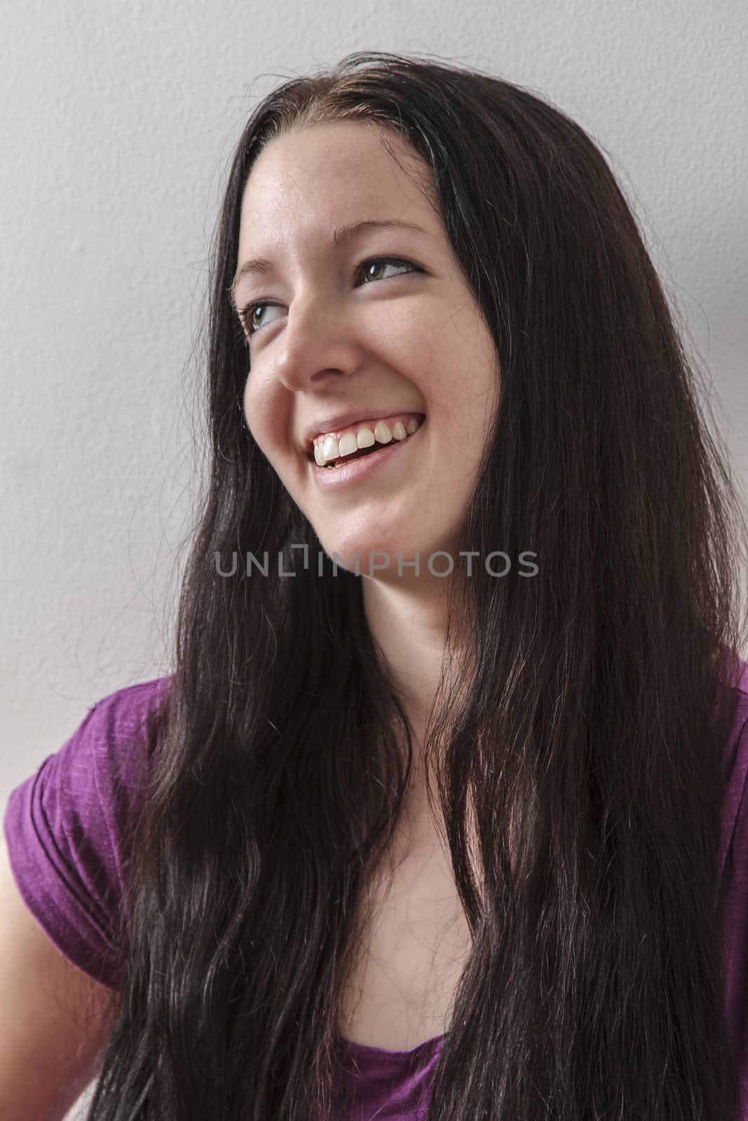 young woman with long black hair against a white wall