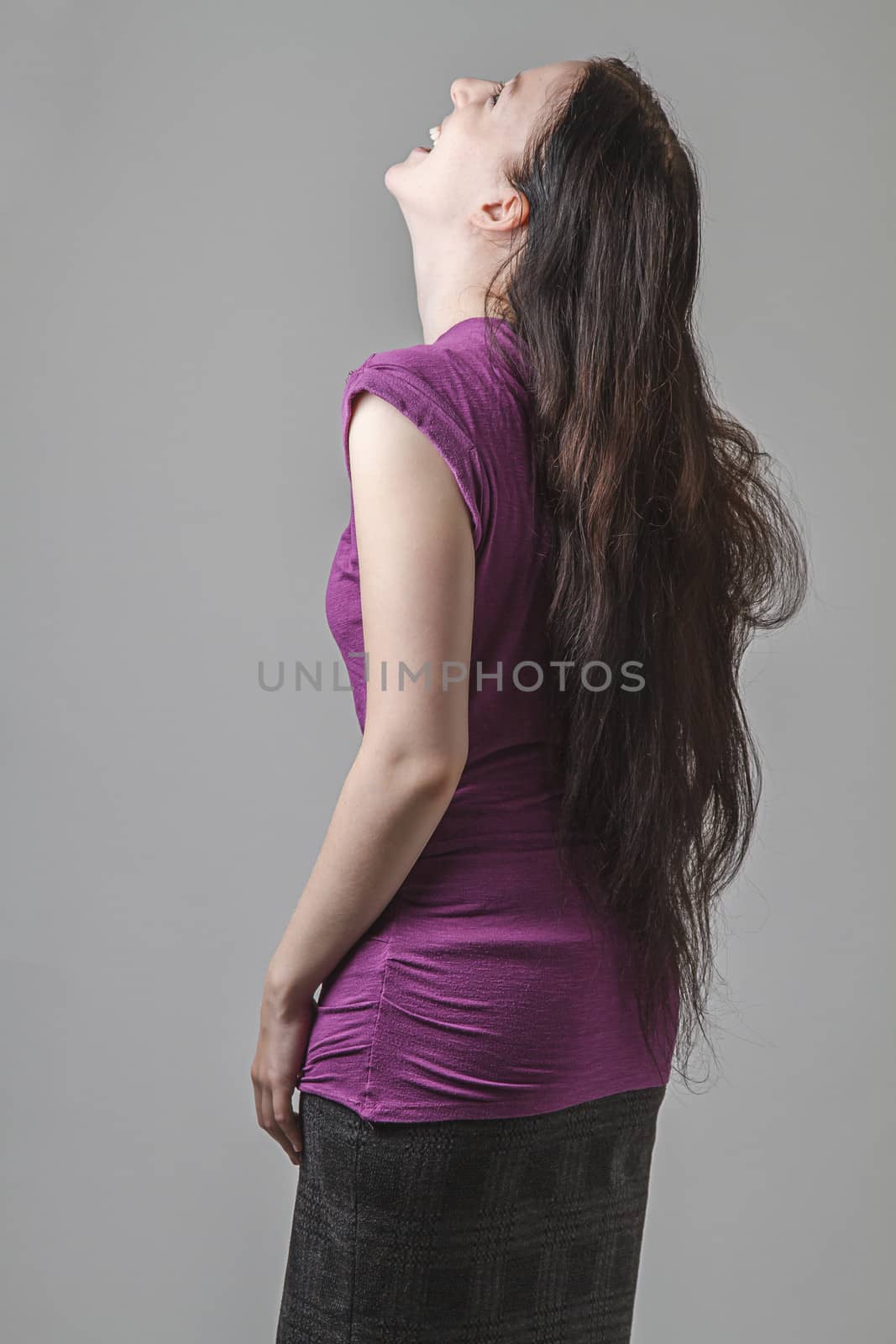 young woman with long black hair and a purple shirt laughing out loud with her head back