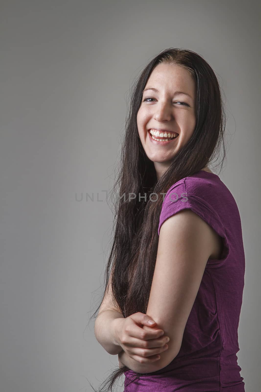 young woman with long black hair and a purple shirt laughing and holding her stomach