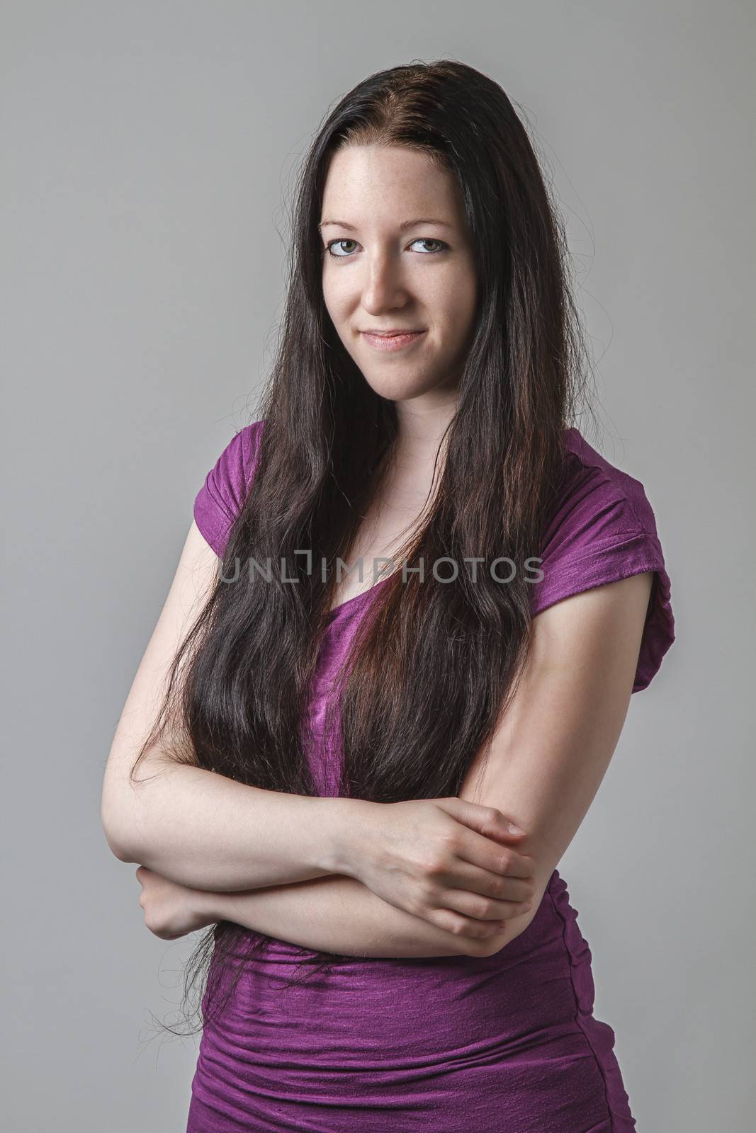 young woman with long black hair and a purple shirt with her arms cross
