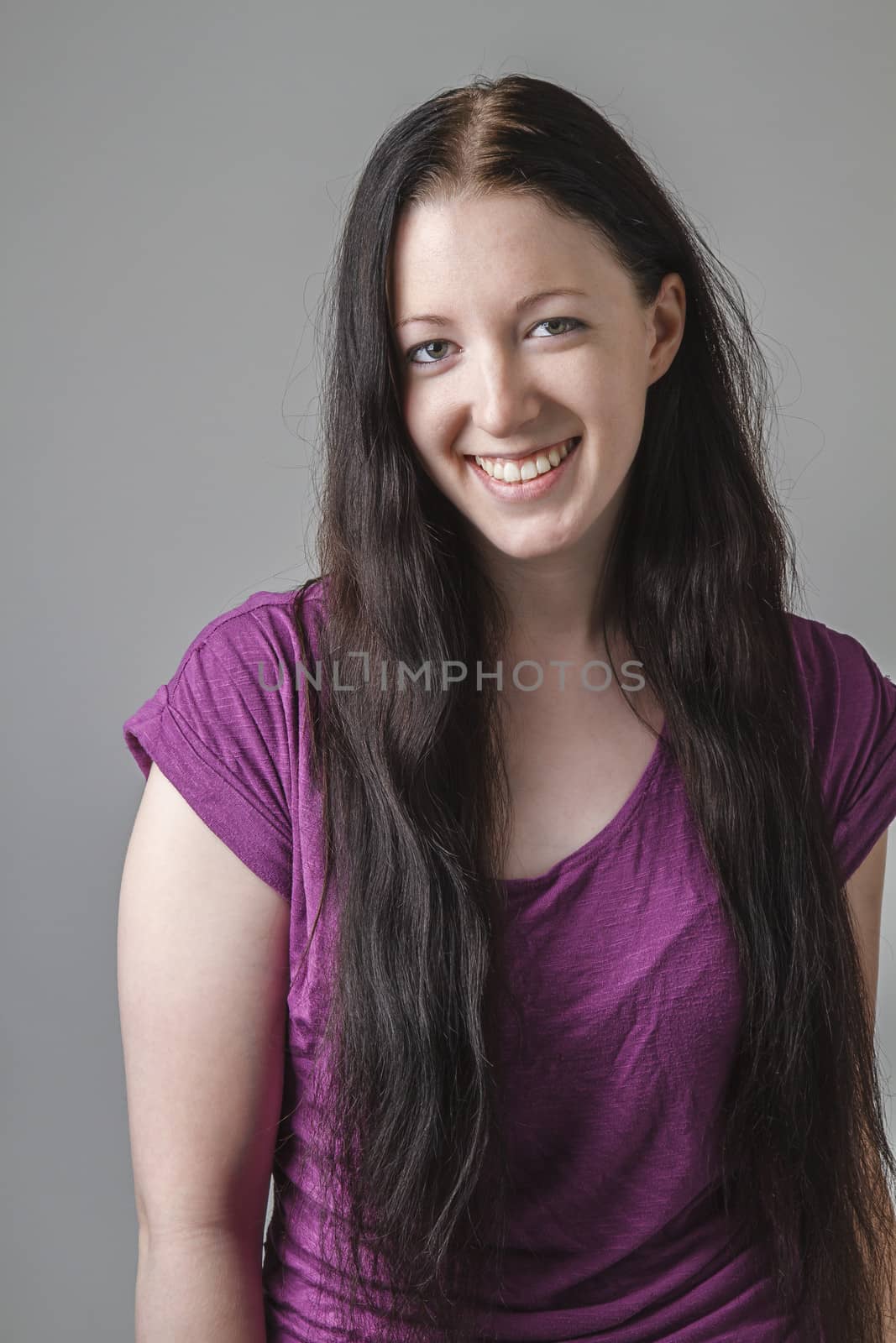 young woman with long black hair and a purple shirt with great big smile