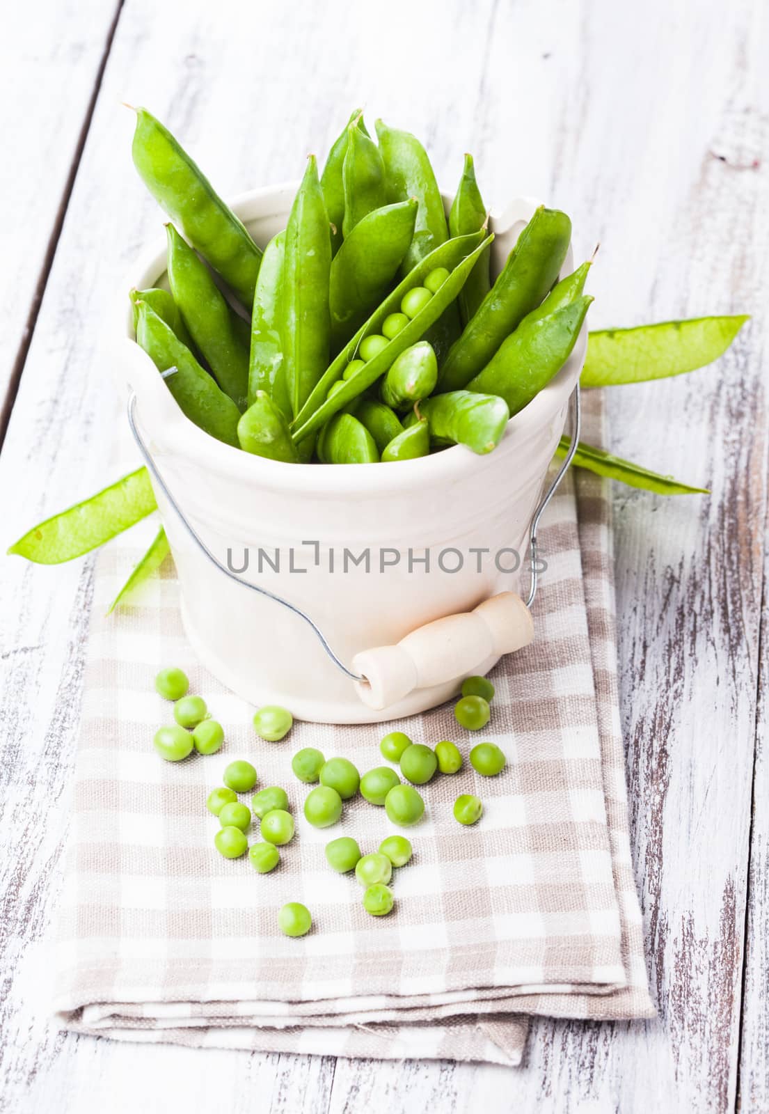 Green pea scattered on the napkin and unpeeled pea