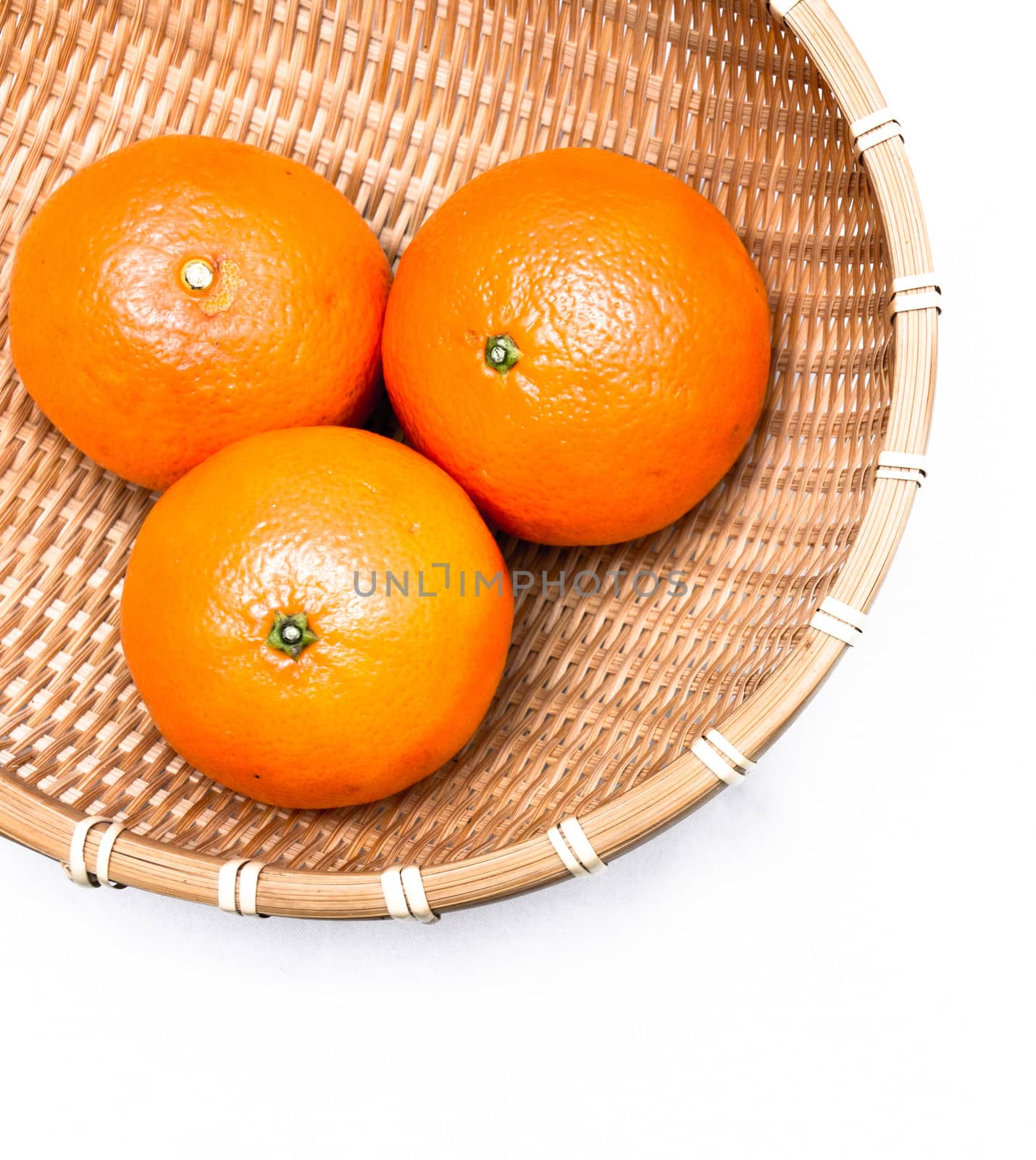 Three oranges lying inside a net basket, isolated on white background