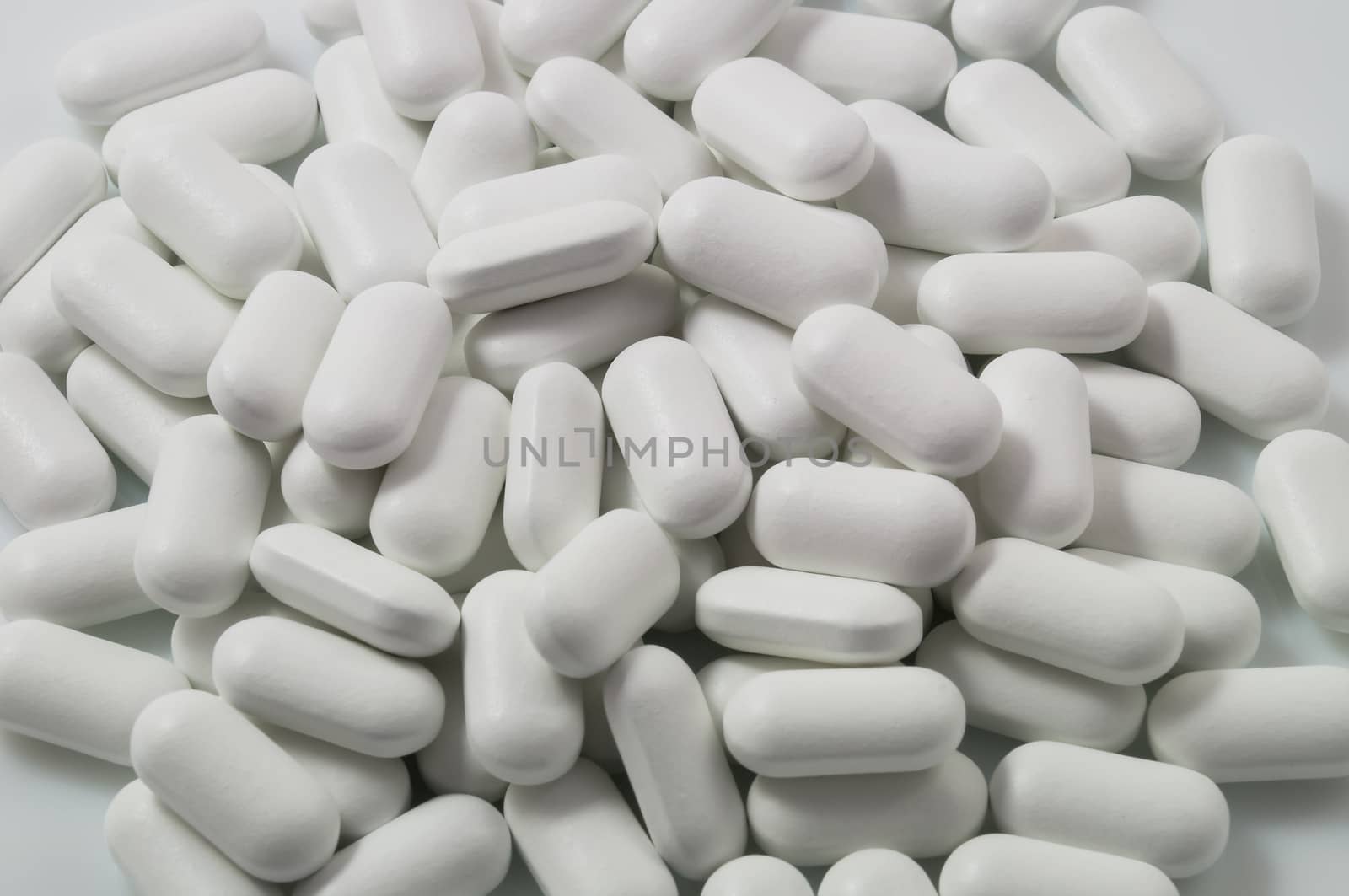 White pills scattered on a white background.