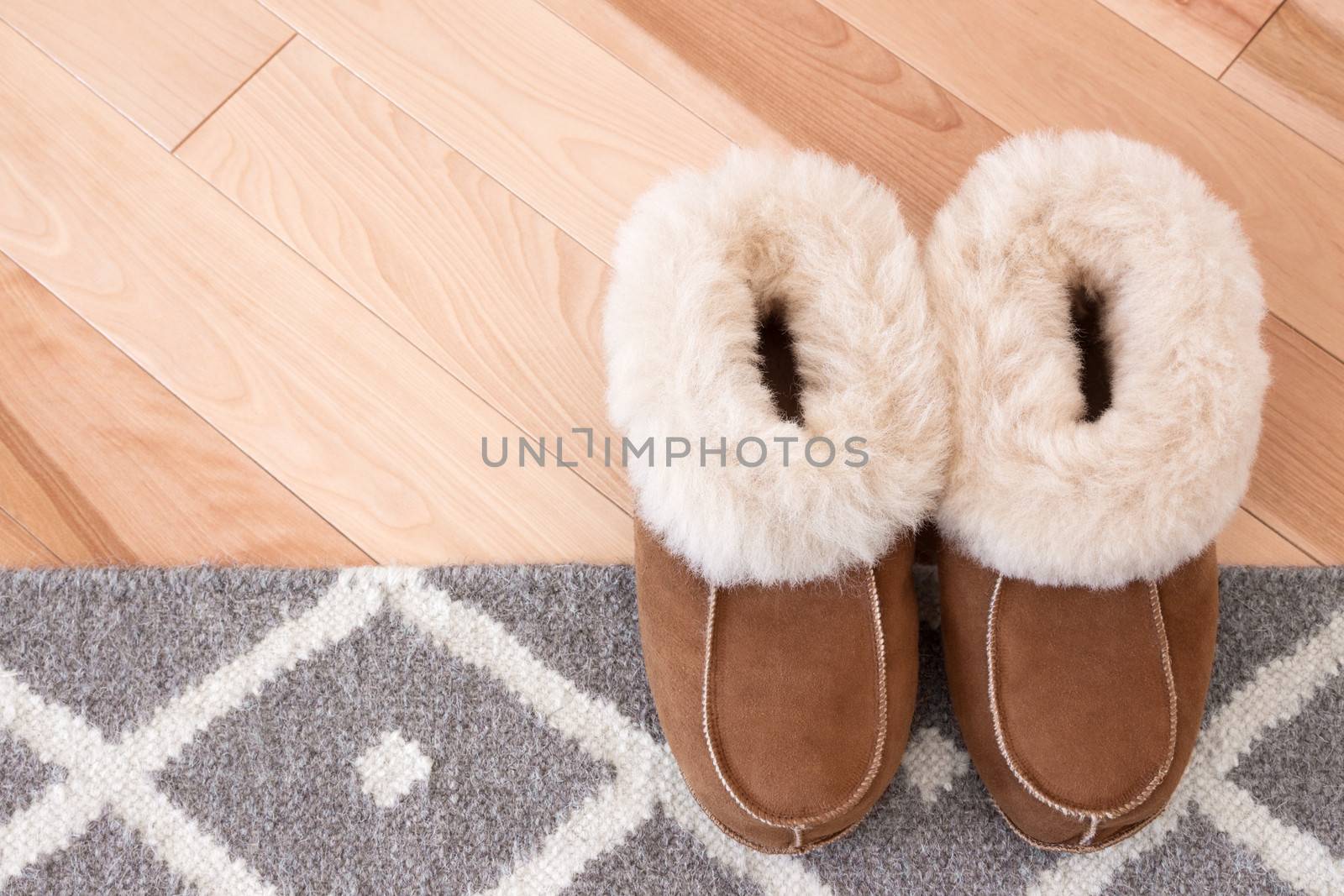 Rug and slippers on wooden floor by anikasalsera
