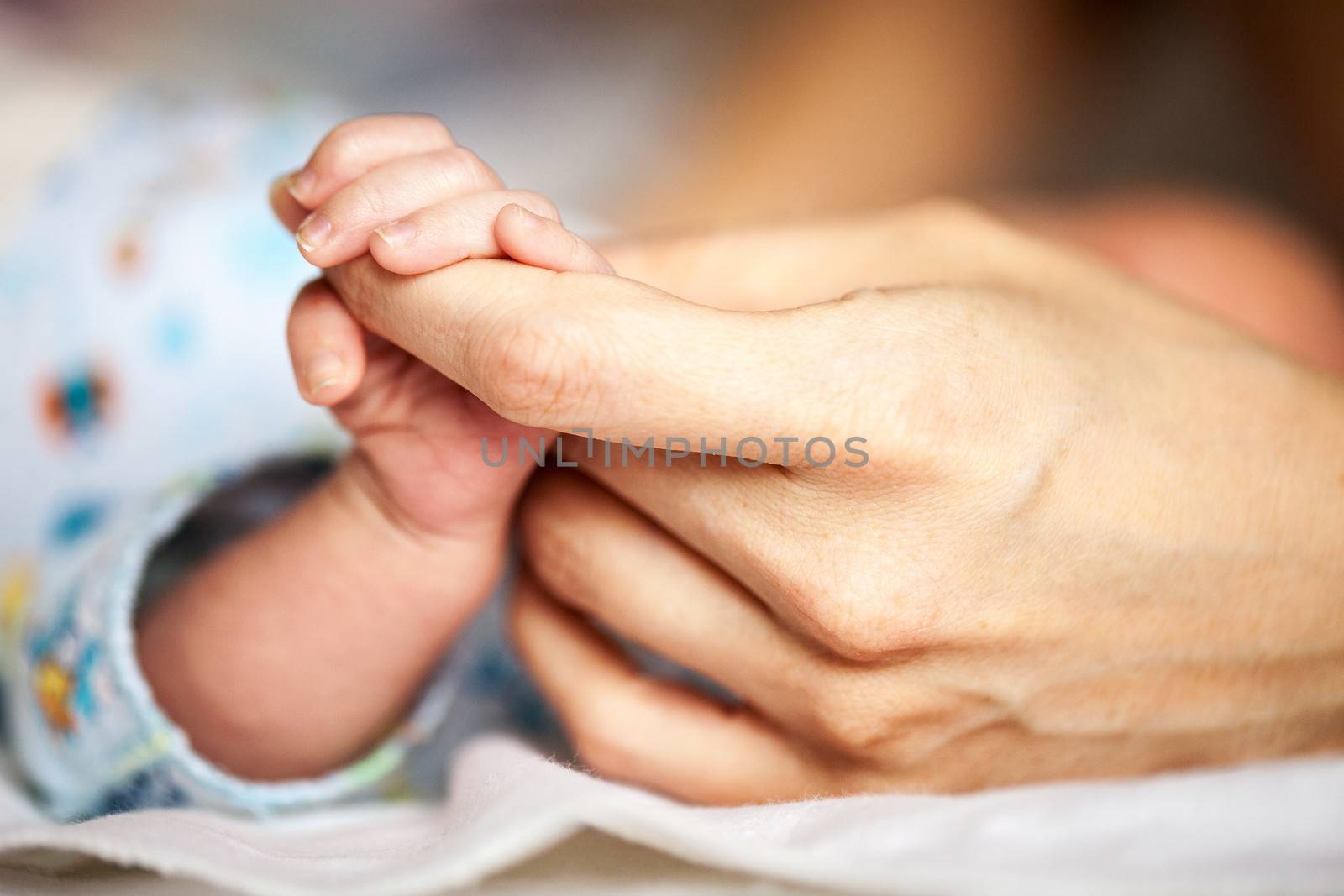 Newborn baby holding mother's hand, image with shallow depth of field