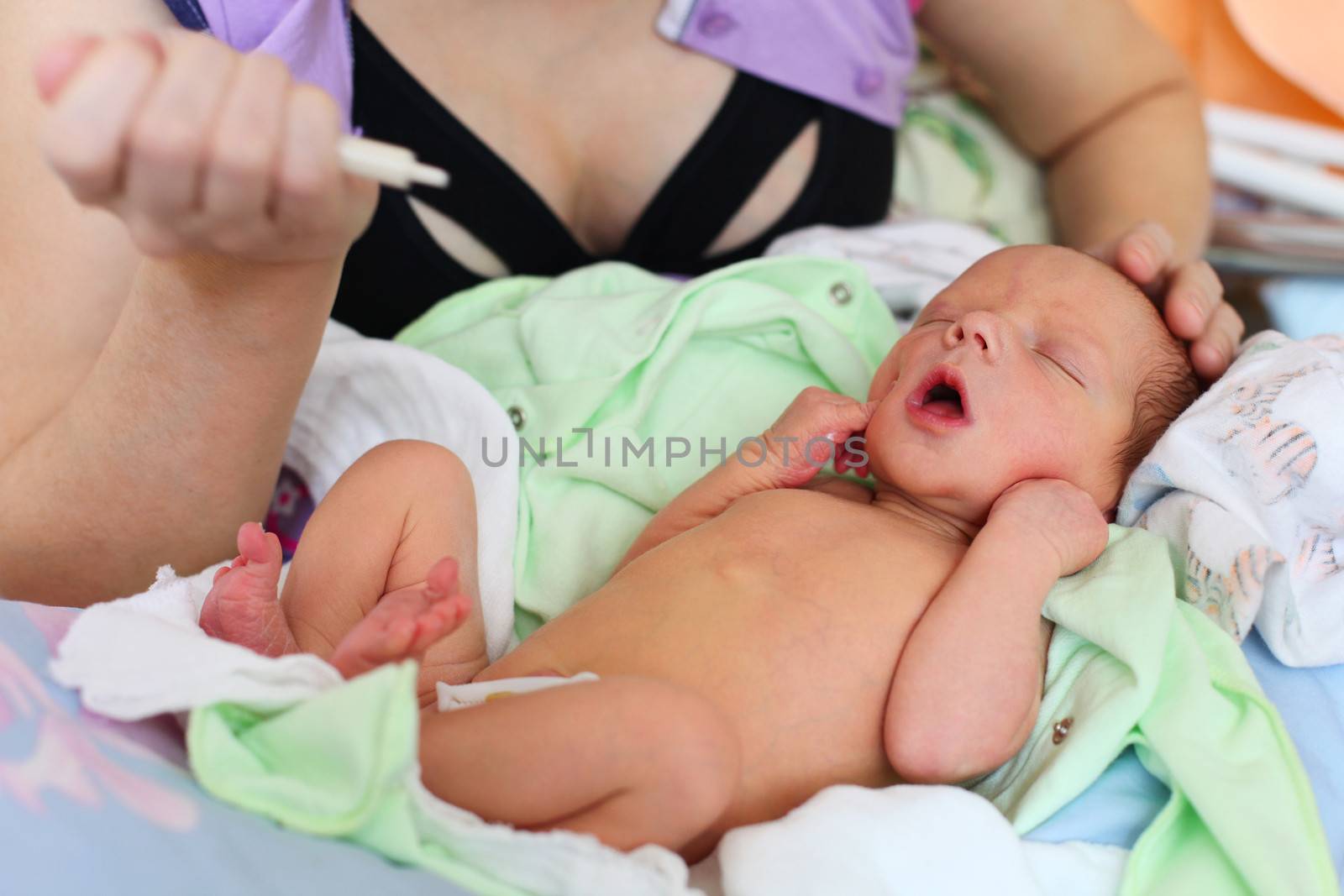 Mother feeding newborn baby milk with syringe at home