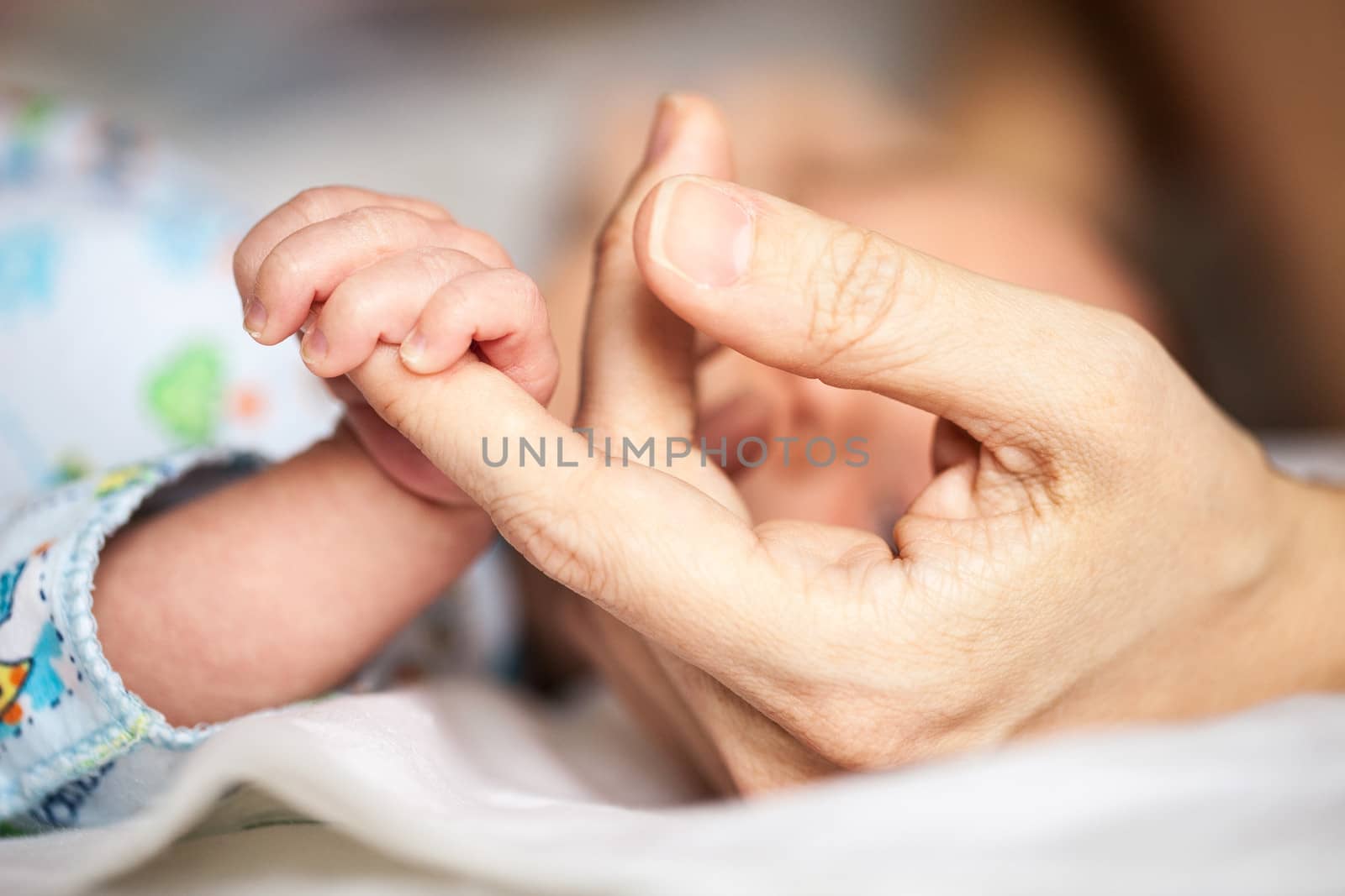 Newborn baby holding mother's hand, image with shallow depth of field