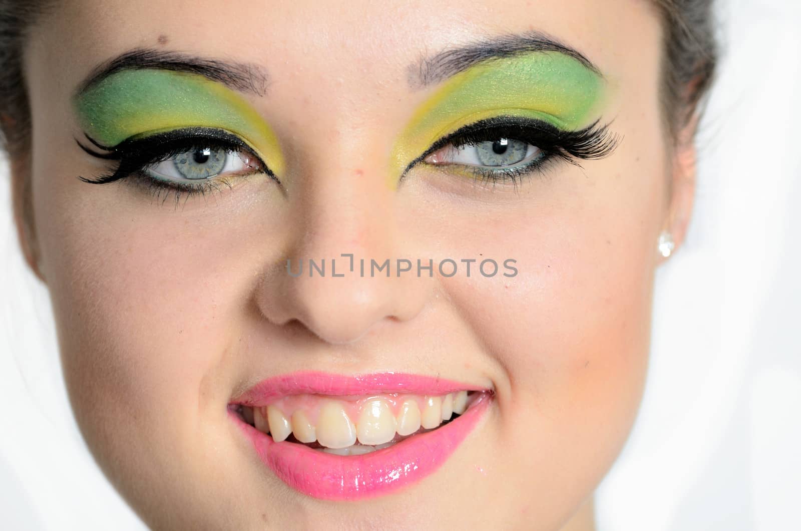 Smiling face photo of young female model with colorful make-up. Young girl with cheering smile.