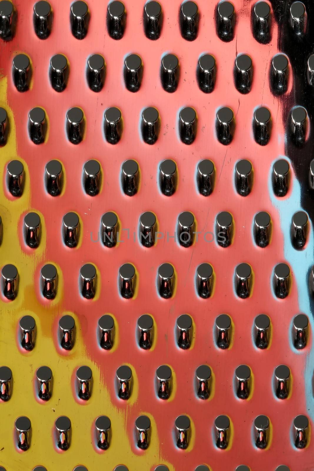 Macro view of a stainless steel cheese grater with reflected colors