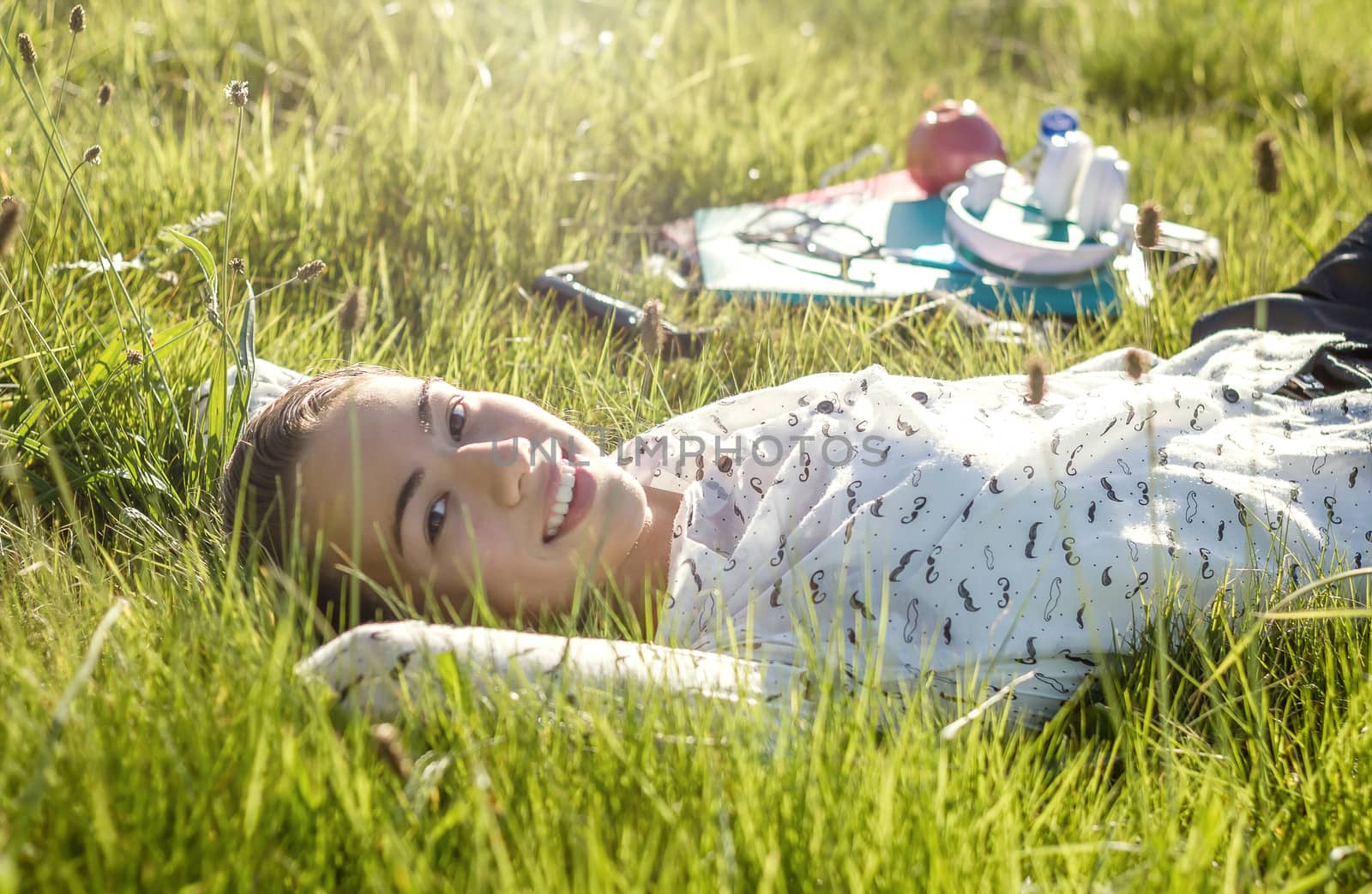 Portrait of beautiful young student lying at the park in a sunny day