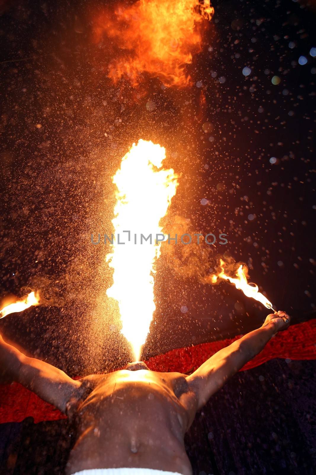 Circus fire-eater blowing a large flame from his mouth