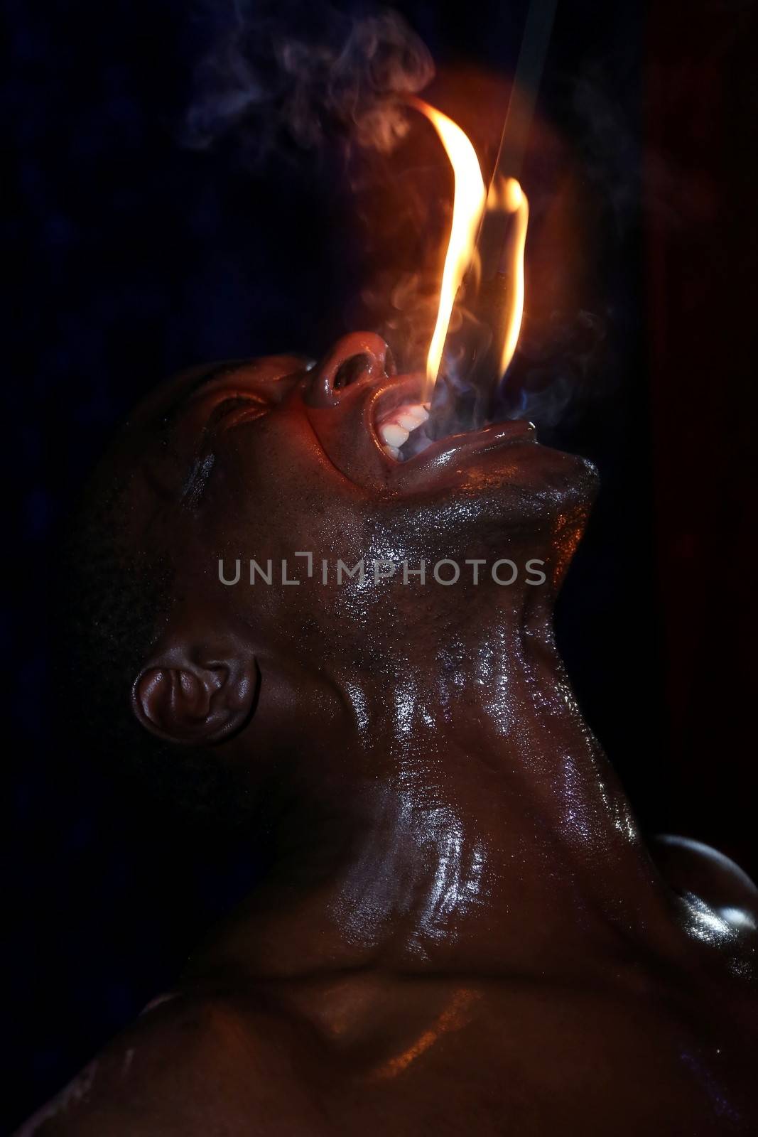 Circus fire-eater eating a fire stick in his mouth