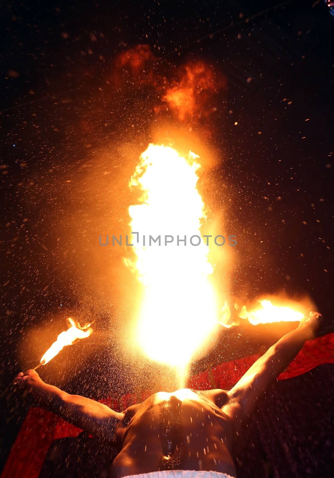 Circus fire-eater blowing a large flame from his mouth