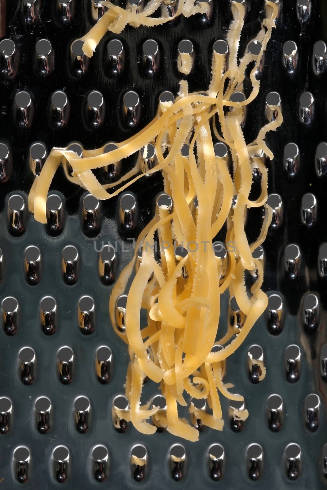 Close up of cheese grated on a stainless steel kitchen grater