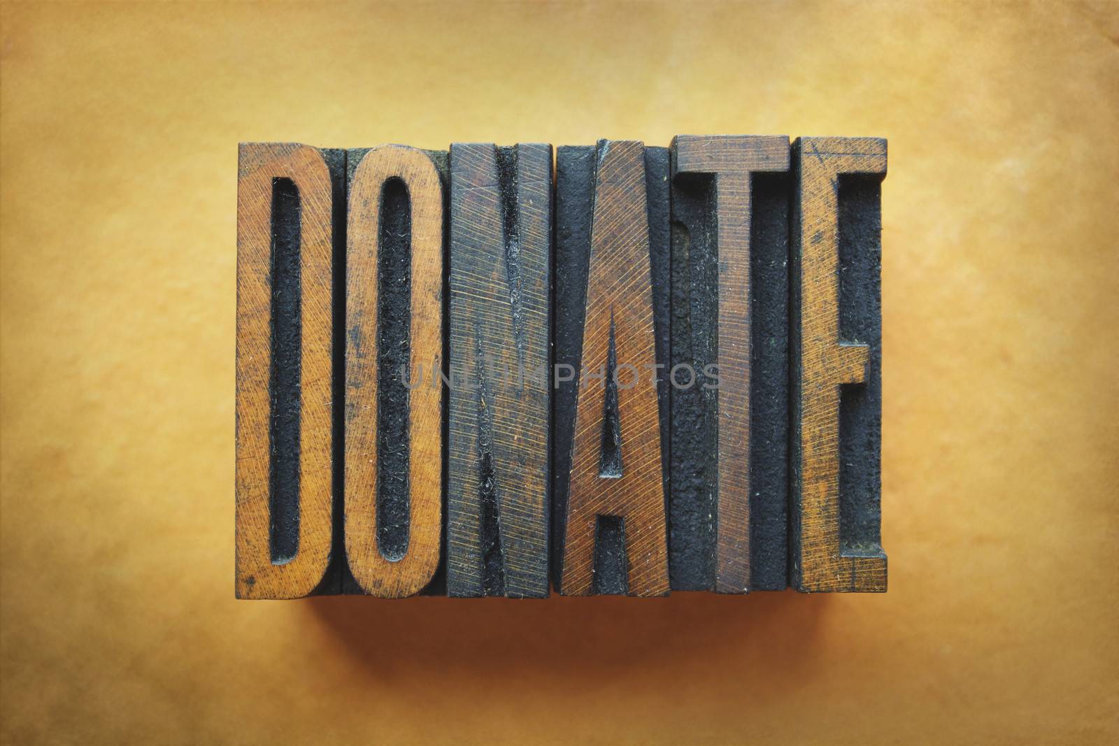 The word DONATE written in vintage letterpress type.