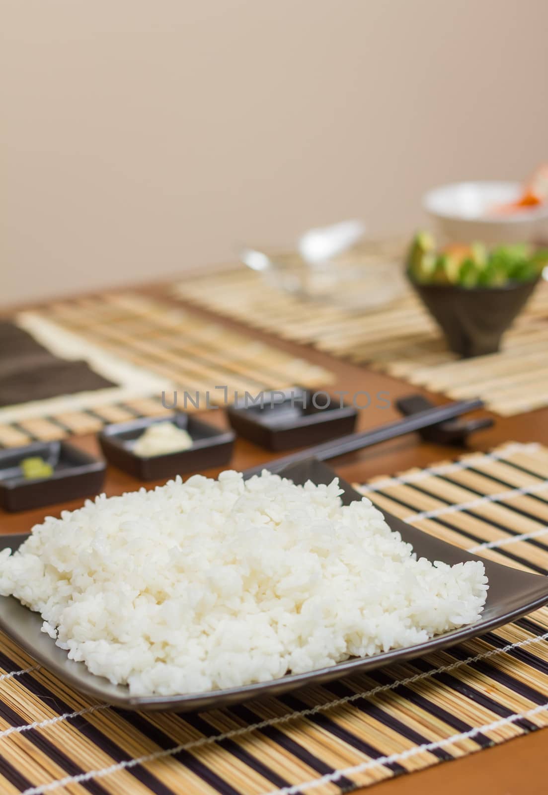 Rice plate in a plate ready to make japanese sushi rolls, with principal ingredients in the background. Selective focus in rice.