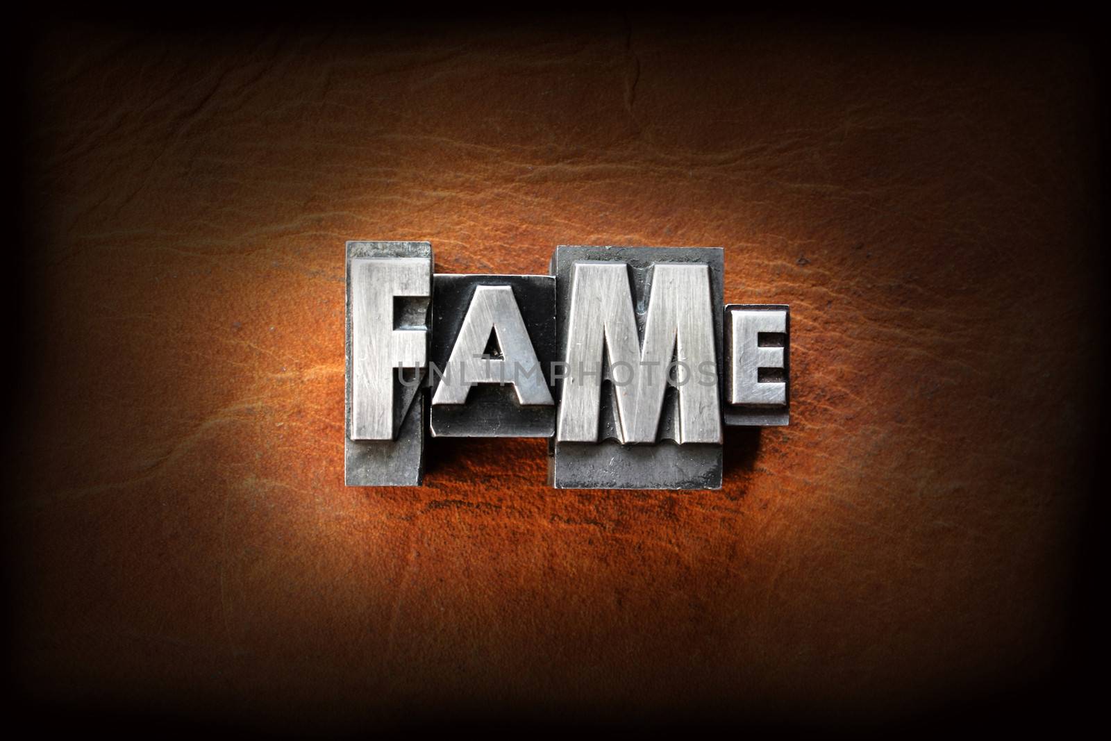 The word fame made from vintage lead letterpress type on a leather background.