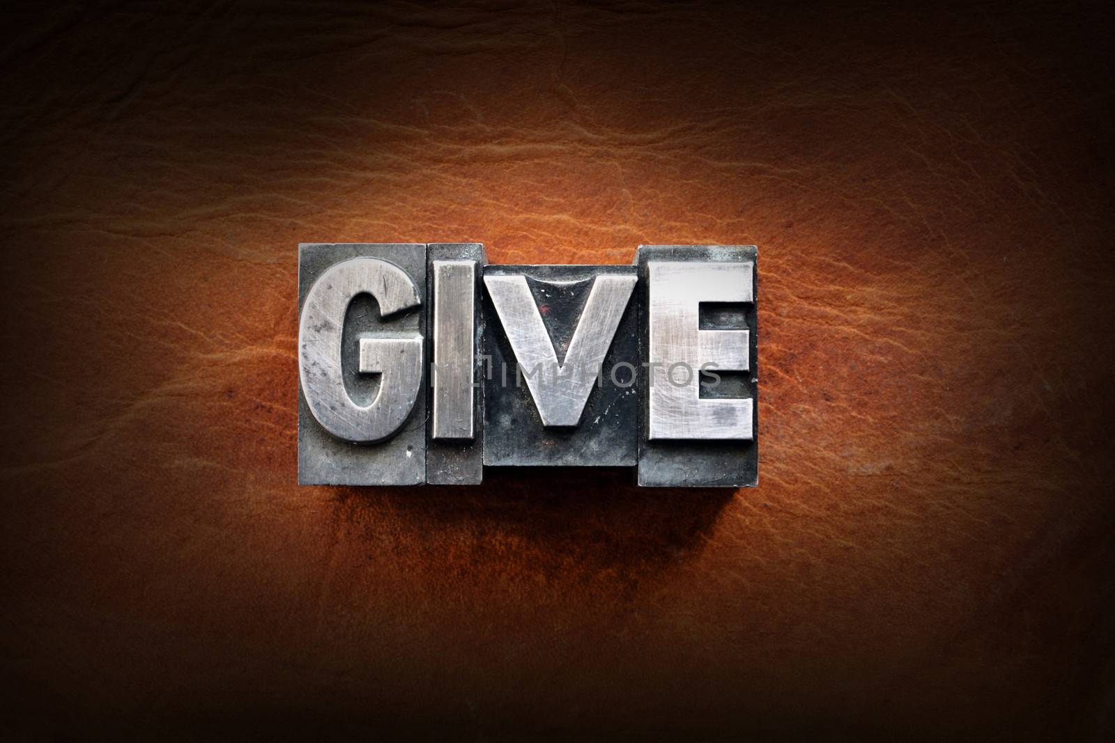 The word give made from vintage lead letterpress type on a leather background.