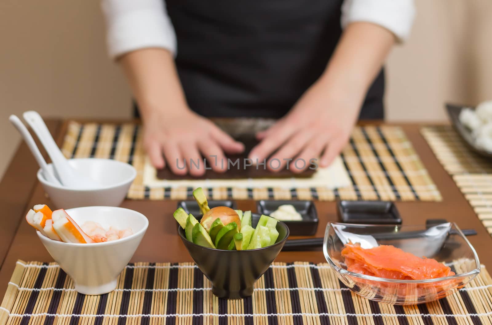 Woman chef ready to prepare japanese sushi rolls, with principal ingredients in the foreground