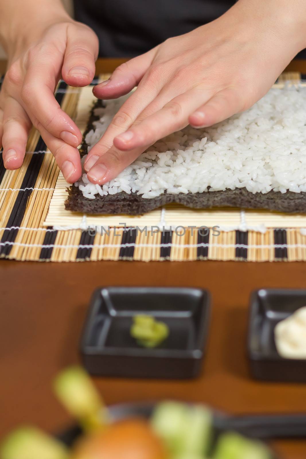 Woman chef filling japanese sushi rolls with rice by doble.d