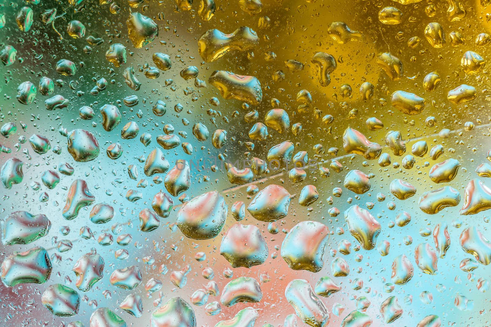 A bright colorful background image of water droplets on a glass surface