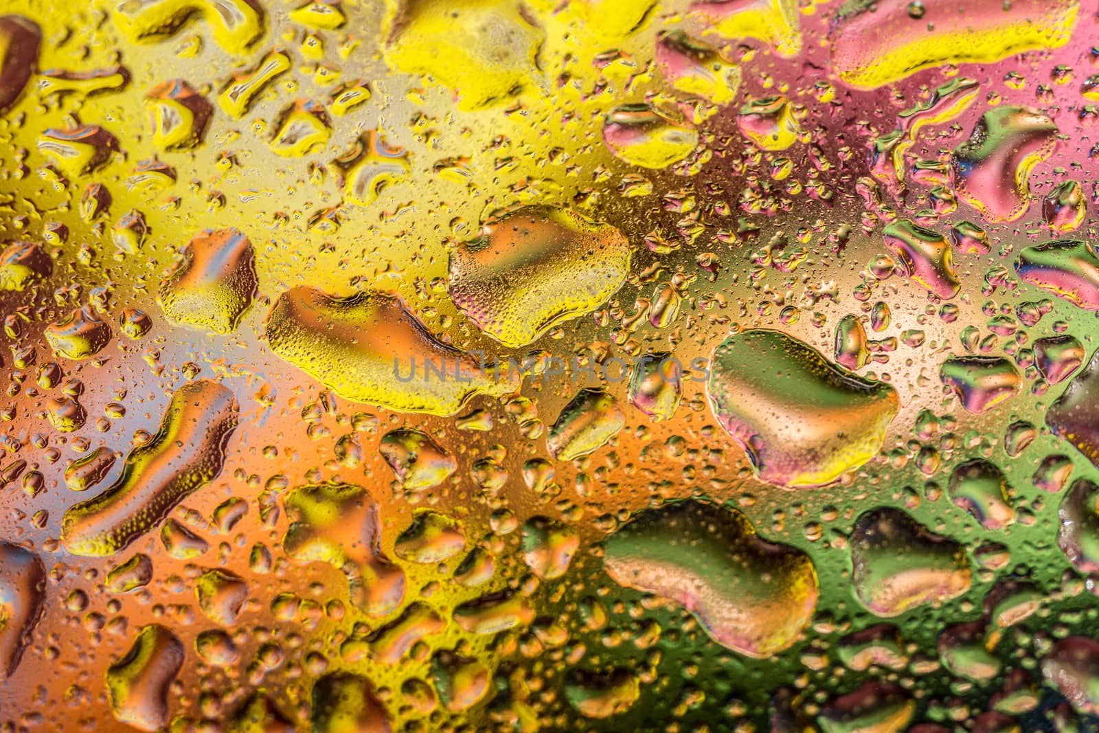 A bright colorful background image of water droplets on a glass surface