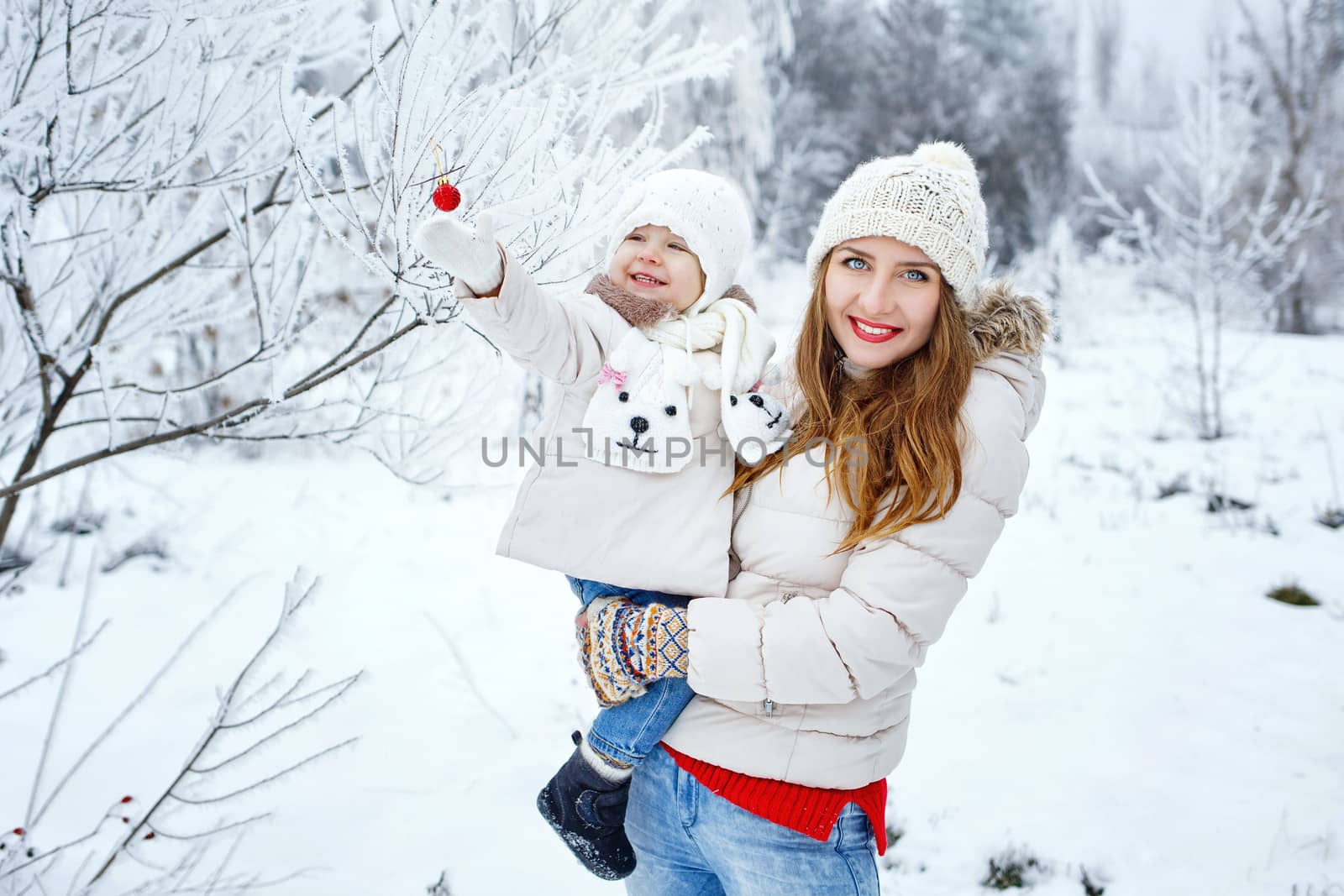Mother holds daughter in her arms in the winter forest