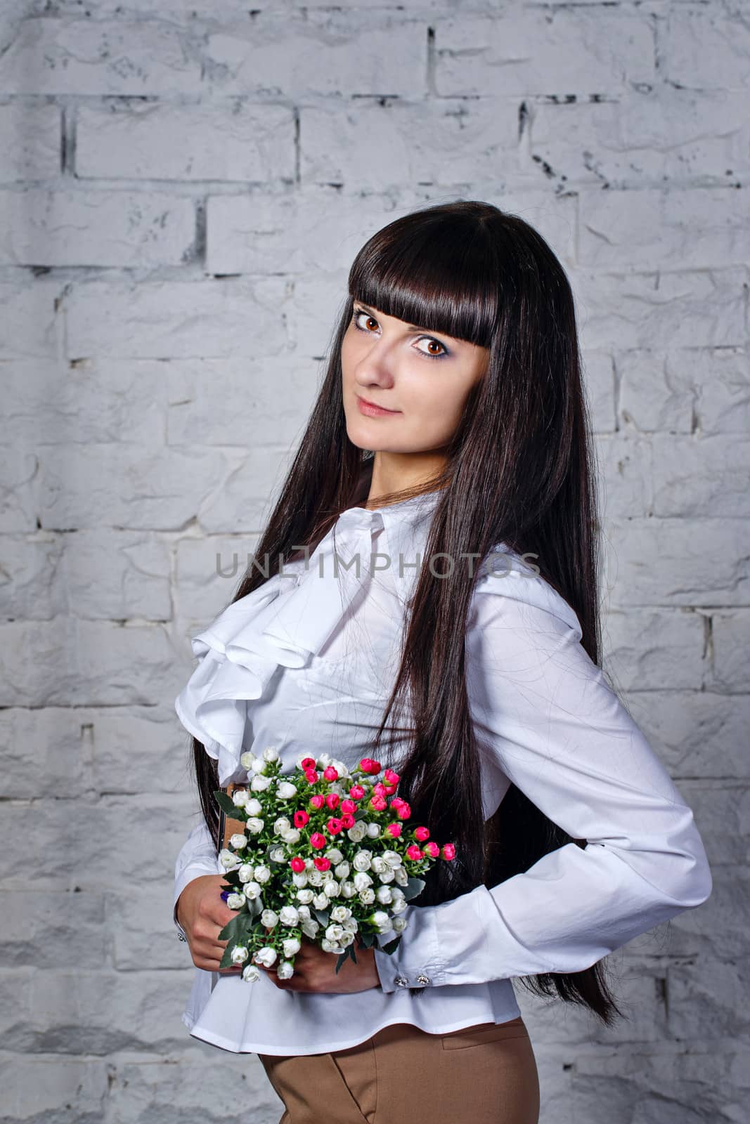 Attractive young brunette girl holding a bouquet of flowers