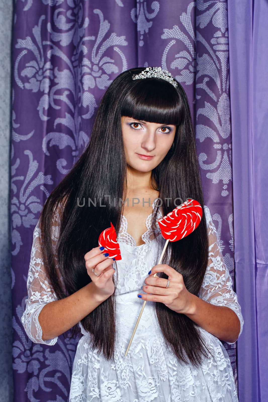 Attractive young brunette girl holding a lollipop with heart-shaped