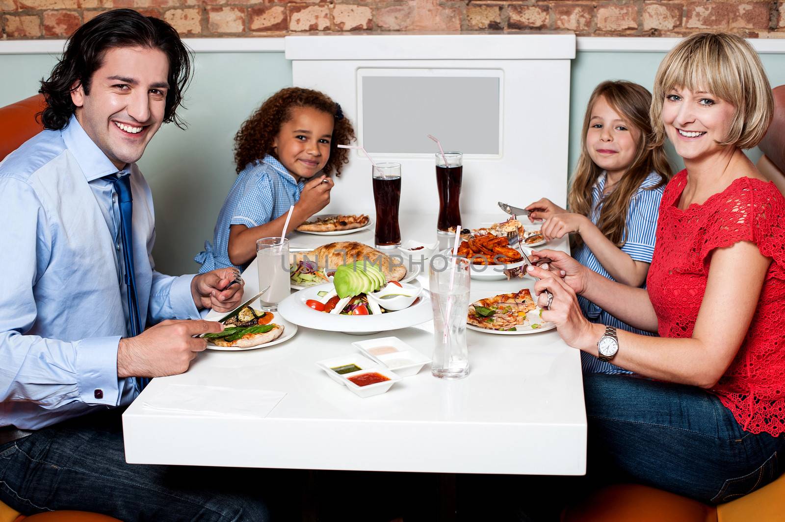 Family eating together in a restaurant by stockyimages